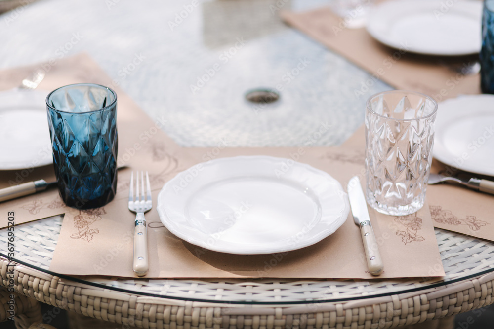 Close up of Served table set at suumer terrace. Cutlery in cafe. Blue glasses Close up of Served table set at suumer terrace. Cutlery in cafe. Blue glasses