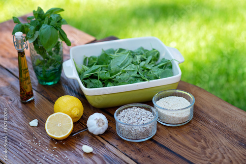 Ingredients for cooking snacks from green spinach sauce with basil, garlic, lemon, sunflower seeds, olive oil and sesame seeds. Organic Health Food Snack or appetizer.