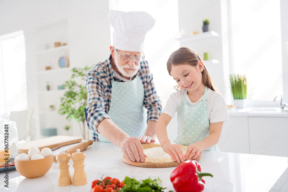 Photo of little girl granddaughter spending time with aged chef grandpa forming dough for family pizza recipe baking cooking together weekend home kitchen indoors Photo of little girl granddaughter spending time with aged chef grandpa forming dough for family pizza recipe baking cooking together weekend home kitchen indoors