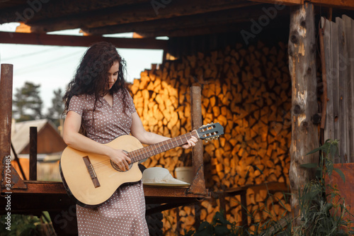 Fototapeta Naklejka Na Ścianę i Meble -  woman playing with guitar and blurred background. Beautiful girl enjoying nature