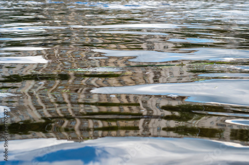 The background of the water surface on the river with a highly distorted reflection of the old building. Large ripples in river water. photo