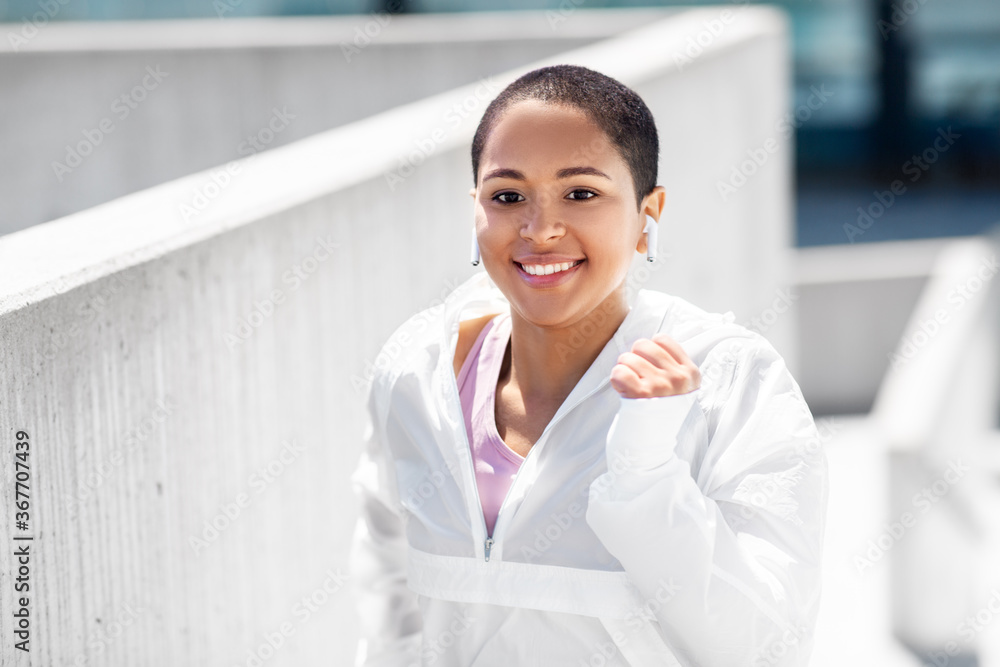 fitness, sport and healthy lifestyle concept - happy smiling young african american woman running upstairs outdoors fitness, sport and healthy lifestyle concept - happy smiling young african american woman running upstairs outdoors