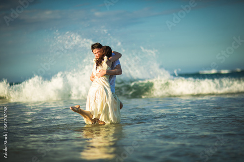 couple in white clothes in water on beach. 