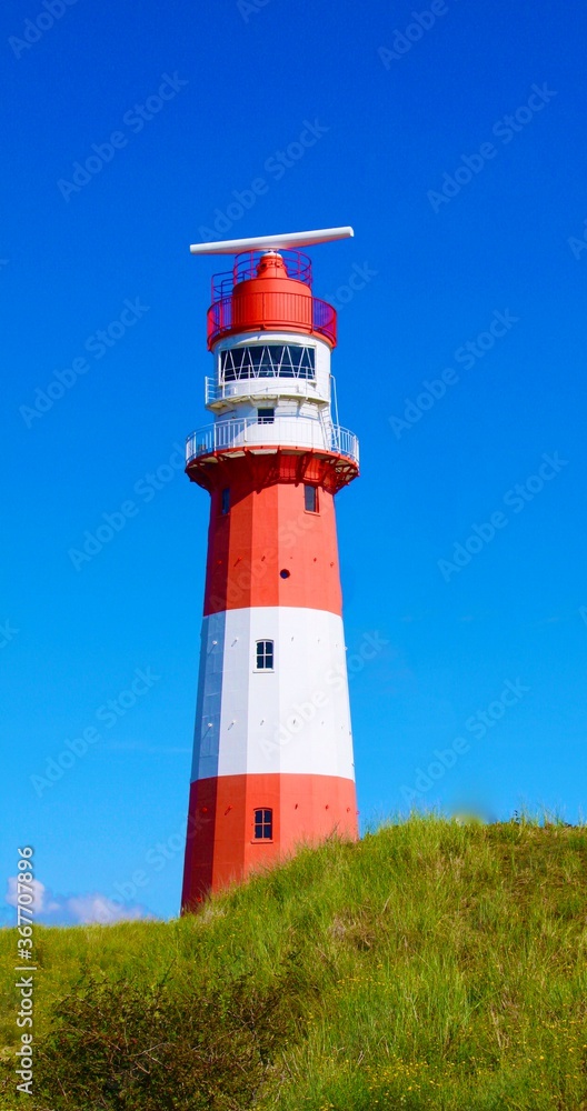 Wunderschöner rot weiß gestreifter Leuchtturm auf der Insel Borkum vor strahlend blauem Himmel in den Dünen. Wunderschöner rot weiß gestreifter Leuchtturm auf der Insel Borkum vor strahlend blauem Himmel in den Dünen.