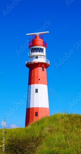 Wundersch  ner rot wei   gestreifter Leuchtturm auf der Insel Borkum  vor strahlend blauem Himmel in den D  nen.