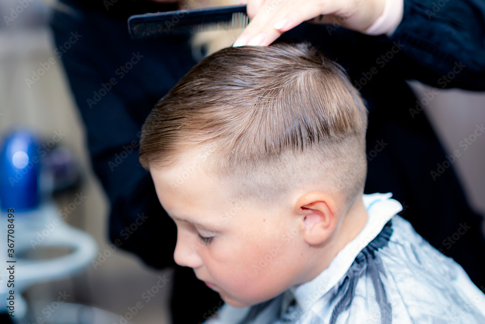Close up caucasian american pretty school boy trendy haircut at bright modern barbershop. Close up caucasian american pretty school boy trendy haircut at bright modern barbershop.