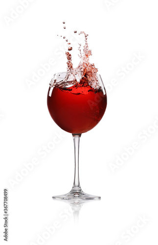 Red wine splashing in glass on white background