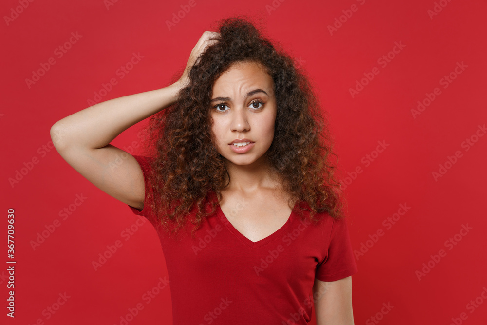 Preoccupied young african american woman girl in casual t-shirt posing isolated on red wall background studio portrait. People sincere emotions lifestyle concept. Mock up copy space. Put hand on head. Preoccupied young african american woman girl in casual t-shirt posing isolated on red wall background studio portrait. People sincere emotions lifestyle concept. Mock up copy space. Put hand on head.