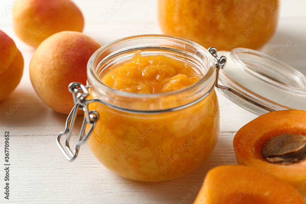 Jar of apricot jam and fresh fruits on white wooden table, closeup Jar of apricot jam and fresh fruits on white wooden table, closeup