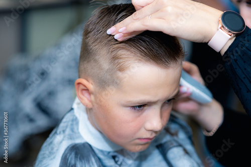 Close up caucasian american pretty school boy trendy haircut at bright modern barbershop.