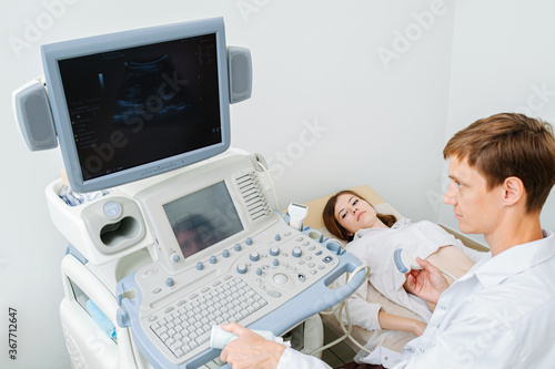 Attentive doctor performing ultrasound scan on a young female patient.