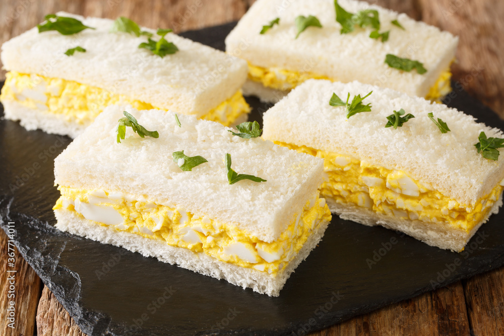 Tamago Sando is a very humble snack, modest, low maintenance and very convenient. The Japanese Egg Sandwich close-up on a slate board. Horizontal Tamago Sando is a very humble snack, modest, low maintenance and very convenient. The Japanese Egg Sandwich close-up on a slate board. Horizontal