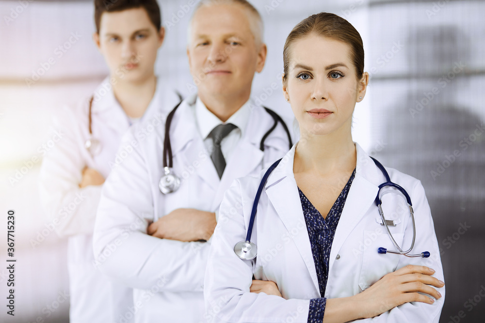 Doctors standing as a team with arms crossed in sunny clinic and ready to help patients. Medical help, insurance in health care, best disease treatment concept Doctors standing as a team with arms crossed in sunny clinic and ready to help patients. Medical help, insurance in health care, best disease treatment concept