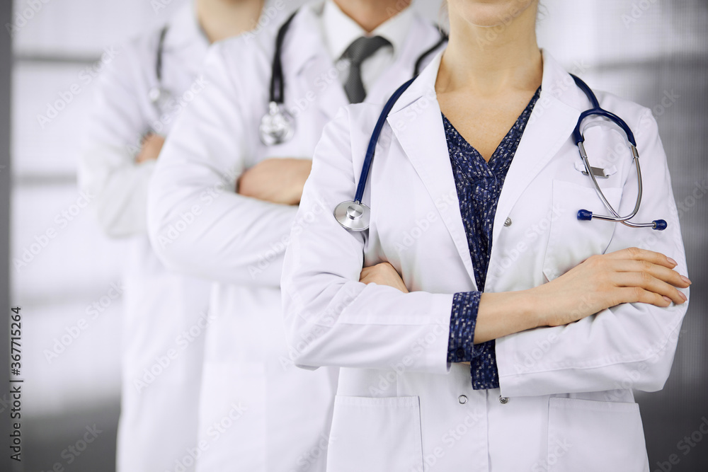 Doctors standing as a team with arms crossed in clinic. Medical help, insurance and medicine concept Doctors standing as a team with arms crossed in clinic. Medical help, insurance and medicine concept
