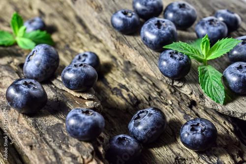 Fresh  juicy  raw blueberries and mint leaves on an old  vintage wooden background. Summer berries  healthy snack.