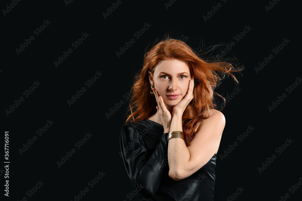 Beautiful young redhead woman on dark background