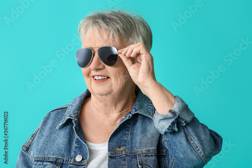 Stylish senior woman on color background © Pixel-Shot