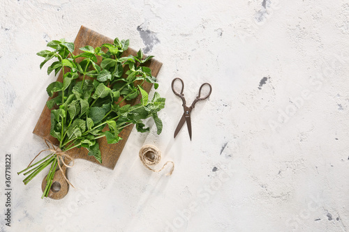 Fresh green mint, scissors and thread on light background