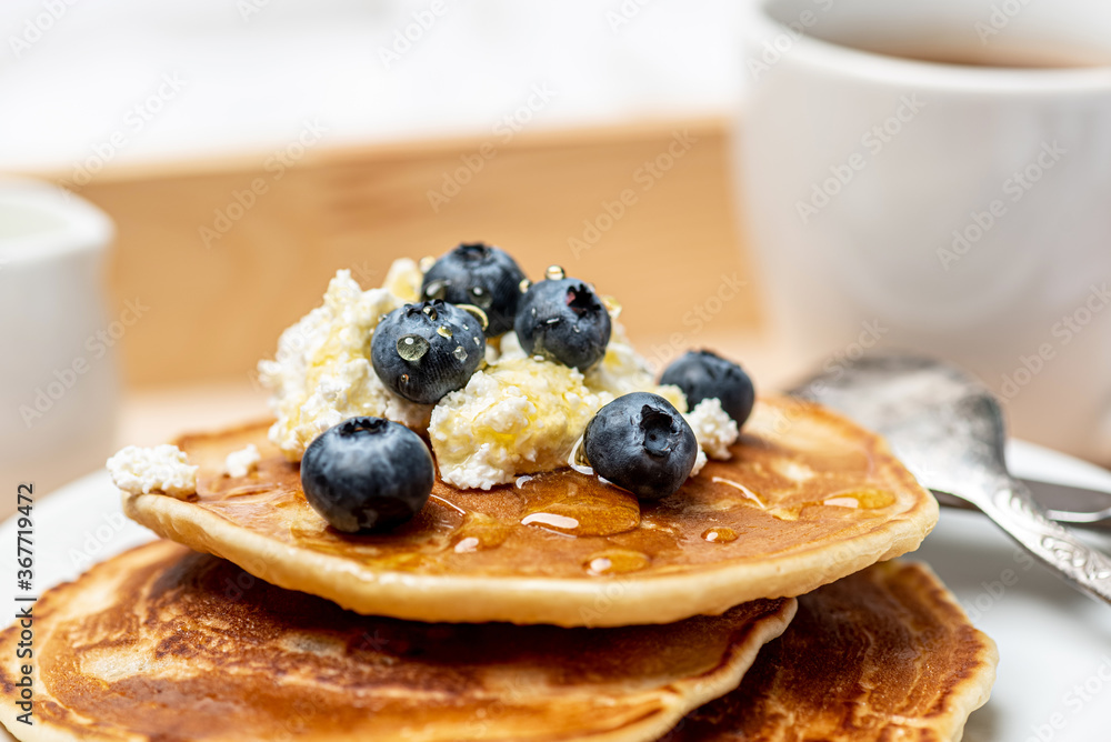 
Tasty breakfast. Delicious pancakes with blueberries, cottage cheese and honey. Close-up.