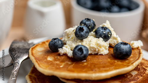  Healthy food. Delicious pancakes with blueberries, cottage cheese and honey for breakfast. Close-up.