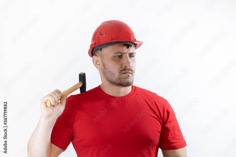 A man in a helmet and a red T-shirt holds a hammer in his hands.