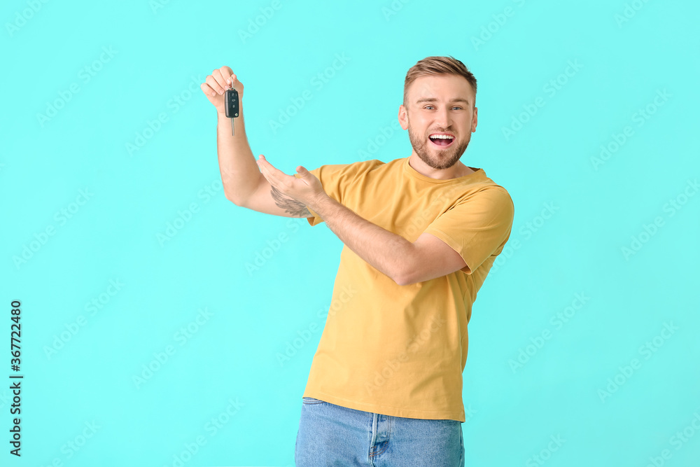 Happy young man with car key on color background Happy young man with car key on color background