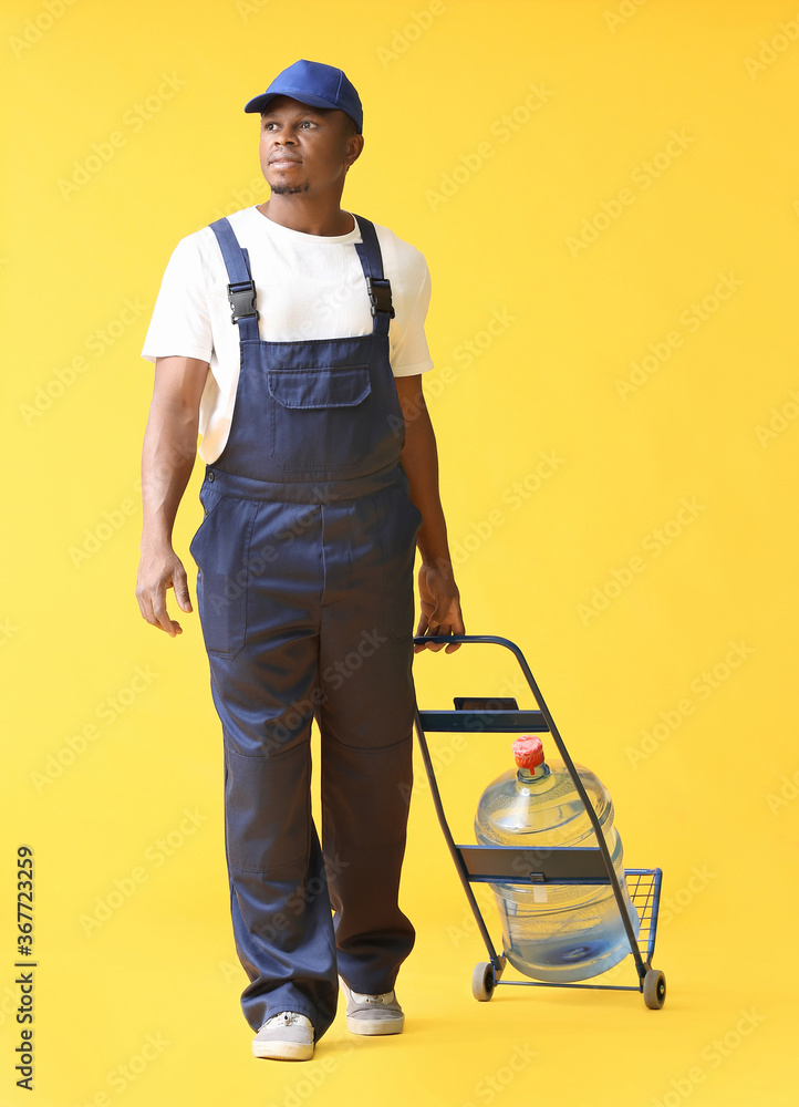 African-American delivery man with bottle of water on color background African-American delivery man with bottle of water on color background