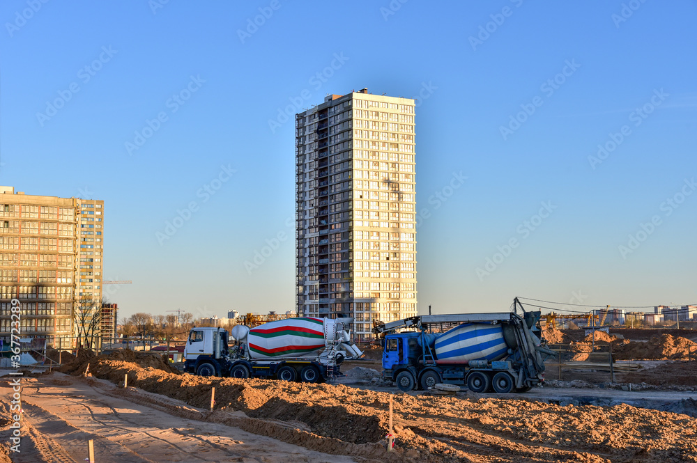 Heavy mixer concrete trucks waiting for to be loaded concrete at a construction site. Mixer truck is delivery cement to the casting place on building Heavy mixer concrete trucks waiting for to be loaded concrete at a construction site. Mixer truck is delivery cement to the casting place on building