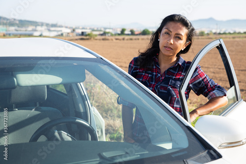 Portrait of driver latino woman next to his car