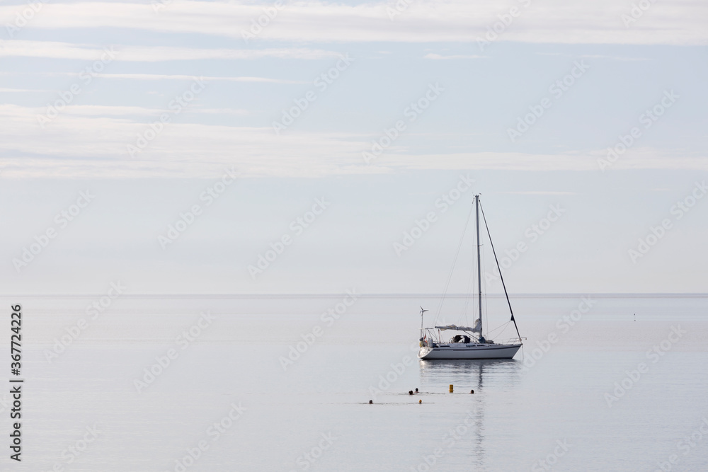 A yacht moored on a calm sea of the Cornwall coast