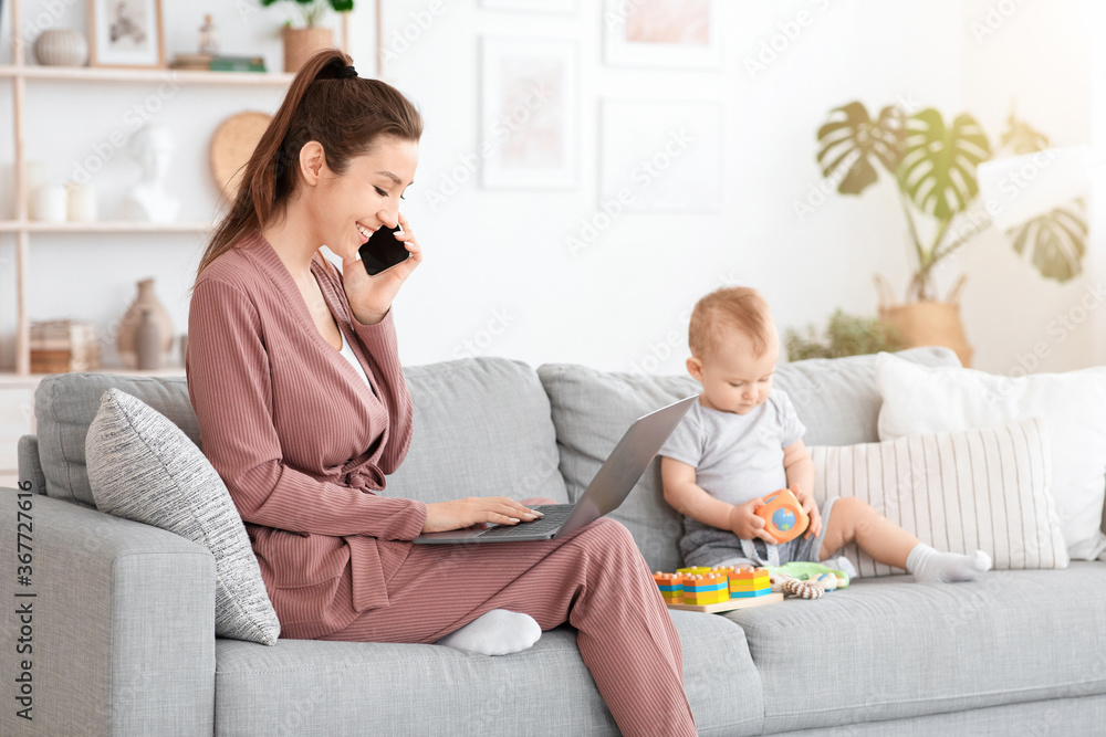 Working Mom. Young Woman Freelancer Using Cellphone And Laptop Next To Baby Working Mom. Young Woman Freelancer Using Cellphone And Laptop Next To Baby