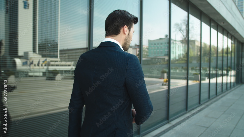 Back view businessman walking with phone. Man using smartphone outdoors Back view businessman walking with phone. Man using smartphone outdoors