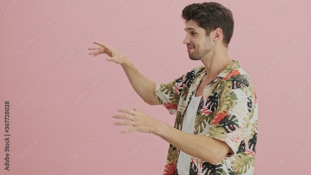 A handsome young man is gesturing over free space isolated over pink background A handsome young man is gesturing over free space isolated over pink background