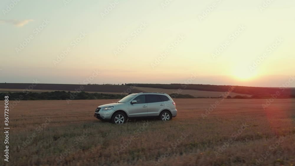 Car drives over field in cloud of dust at high speed rising in rays of sunset summer aerial view drone. Car of nature lens flare. Drive, relax. Travel, tourism in summer. Freedom. Safari Car drives over field in cloud of dust at high speed rising in rays of sunset summer aerial view drone. Car of nature lens flare. Drive, relax. Travel, tourism in summer. Freedom. Safari