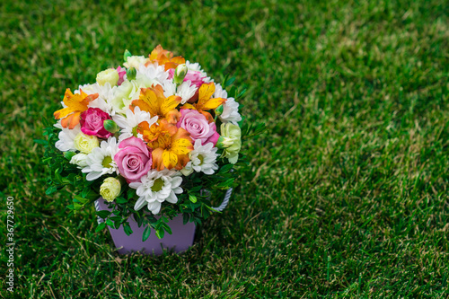 Canvas Print bouquet of colorful flowers in hatbox on lawn. place for text.