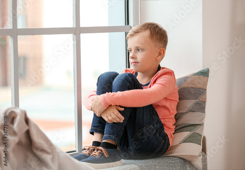Little boy with autistic disorder sitting near window at home