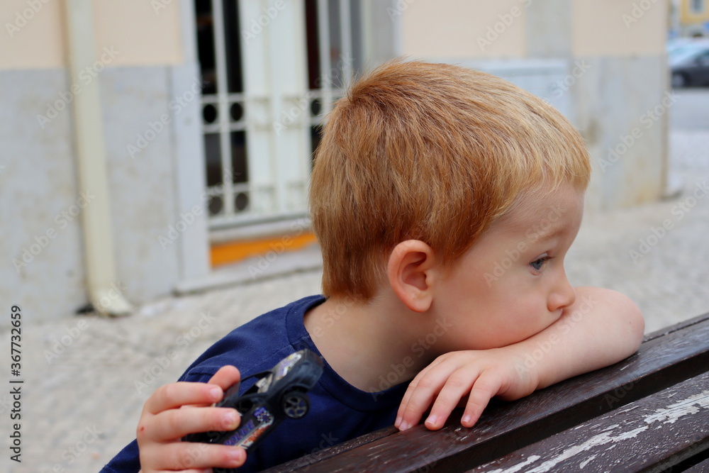 Portrait of a charming blond boy. A three-year-old boy is leaning on his arm and looking into the distance. Portrait of a charming blond boy. A three-year-old boy is leaning on his arm and looking into the distance.