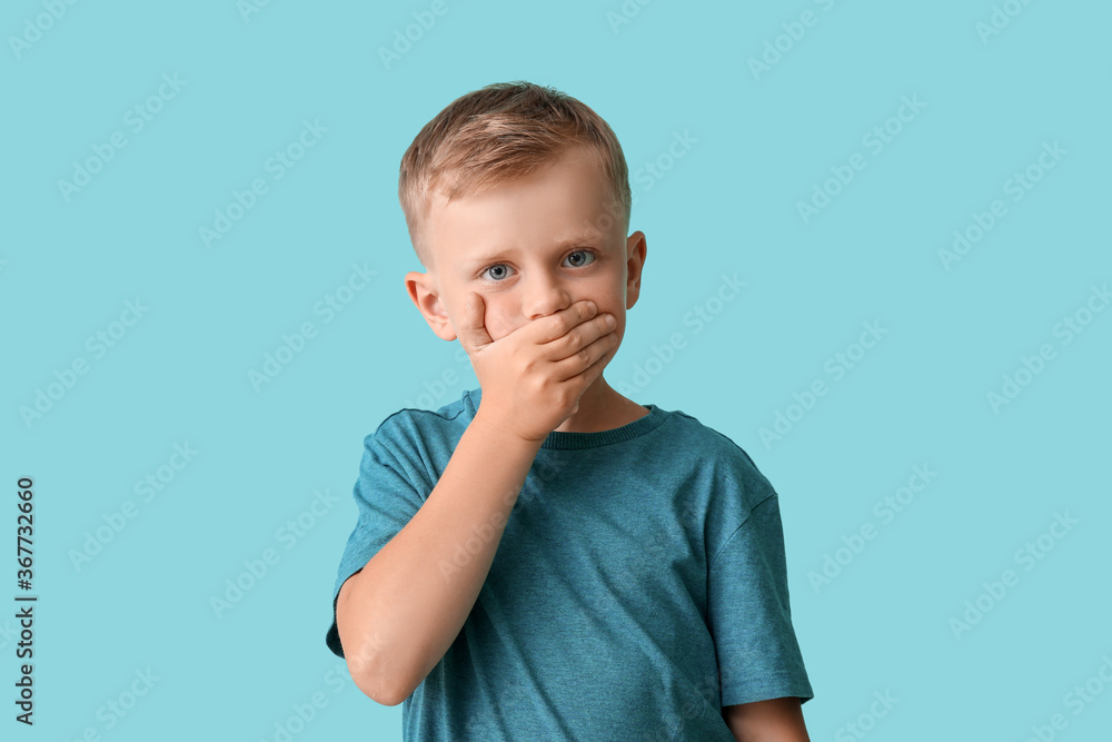 Little boy with autistic disorder covering mouth on color background Little boy with autistic disorder covering mouth on color background