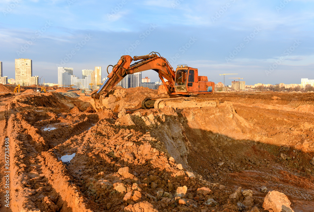 Obraz premium Excavator during excavation at construction site. Backhoe on Earthworks. Heavy Construction Equipment Machines in Action. Big Digger Digging the Foundation House