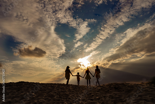 Family on the beach  sunset and beautiful cloudy sky  silhouettes  happiness