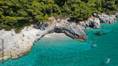 Aerial drone photo of secluded turquoise paradise island rocky cove covered up with pine trees