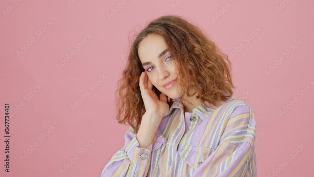 A beautiful young woman is posing to the camera isolated over pink background in studio A beautiful young woman is posing to the camera isolated over pink background in studio