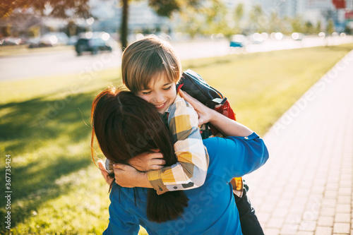 A mother hugs her young son on the way to school, and a mother and boy say goodbye before school. Concept of education and training, return to school