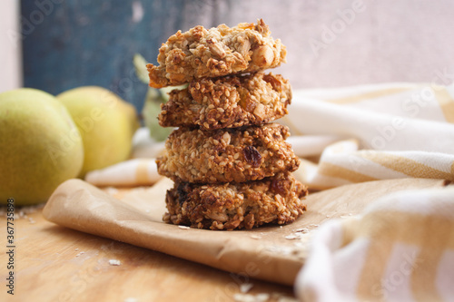 Homemade oatmeal cookies folded in a pile on baking paper with pears behind. Wooden background
 photo