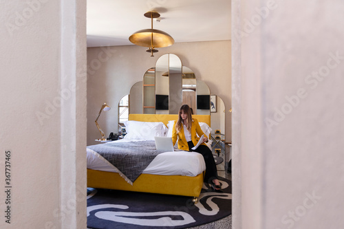 Serious woman using laptop in modern hotel