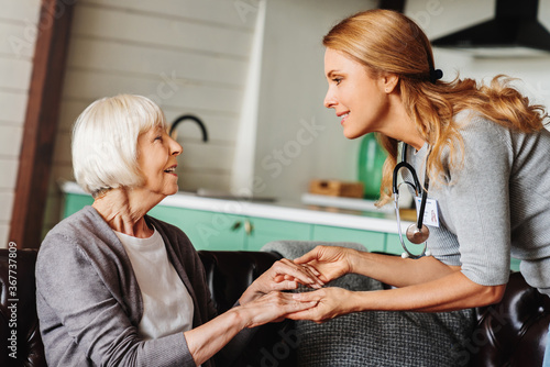 Adult female doctor visiting senior woman at home. Elderly assistance concept