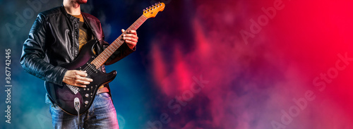 Guitar player performs on stage. Rock guitarist plays solo on an electric guitar. Artist and musician performs like rockstar. photo