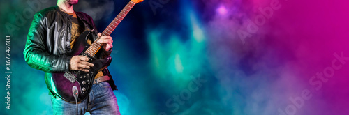 Guitar player performs on stage. Rock guitarist plays solo on an electric guitar. Artist and musician performs like rockstar. Black and white version. Green and pruple version. Panoramic image.