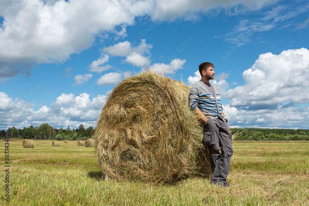 Handsome young man standing by a haystack. Handsome young man standing by a haystack.