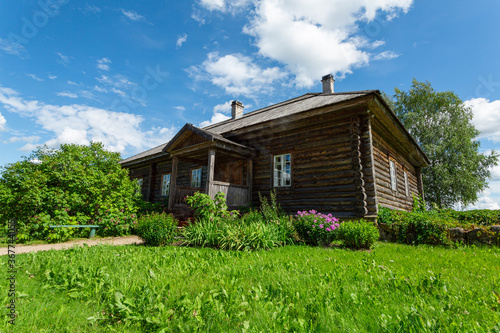 Old wooden Russian house on the green lawn in summer. Horizontal image.